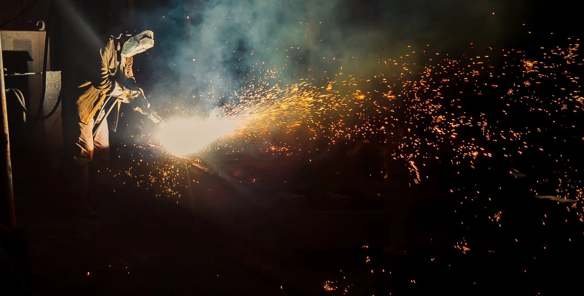 Ein Mann schweißt im Dunkeln, während Funken um ihn herum sprühen